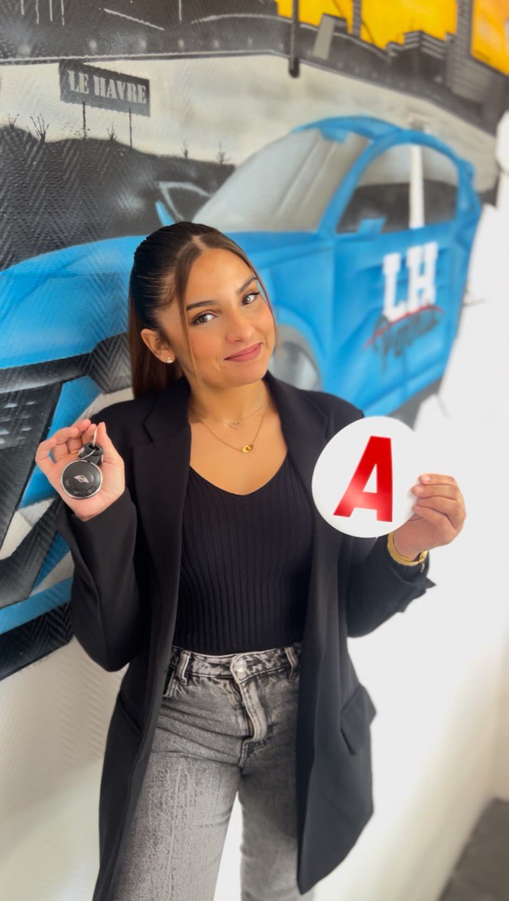 Élève devant le mur peint de l'agence : voiture LH Permis et skyline du Havre